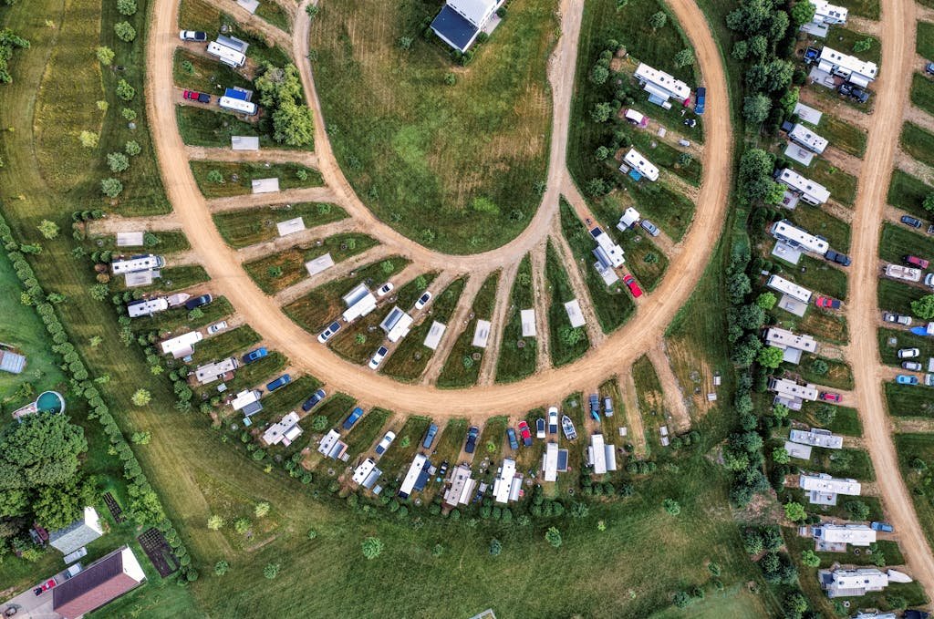 Aerial shot of a camper park with RVs parked in a semi-circle arrangement in lush green surroundings.